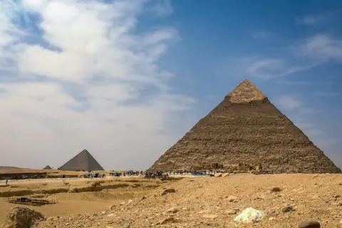 To af pyramiderne i Giza i ørkensand under blå himmel med drivende skyer