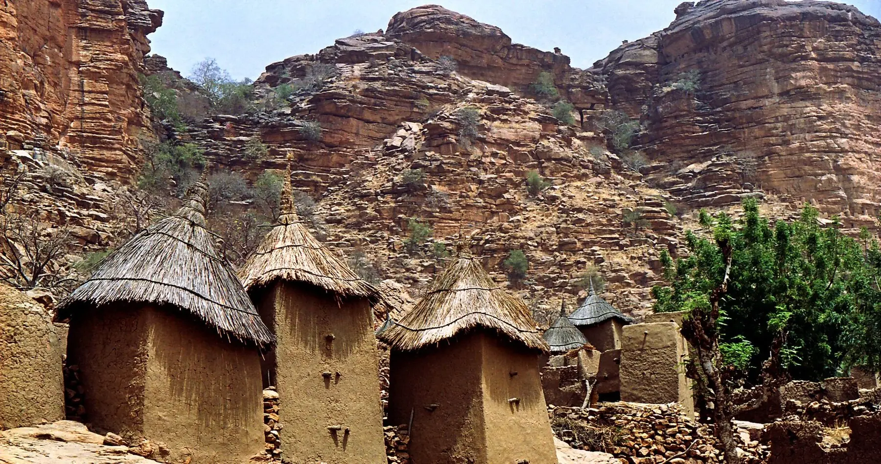 Dogon-folkets små forrådshuse af ler med stråtag neden for røde sandstensklipper ved Bandiagara