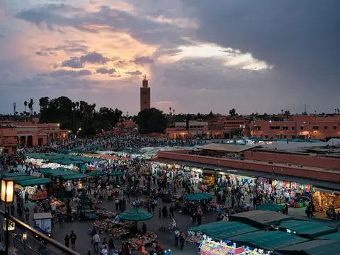 Markedsboder og folkemylder på Jemaa el-Fnaa-pladsen i skumringen med Koutoubia-minareten bagved