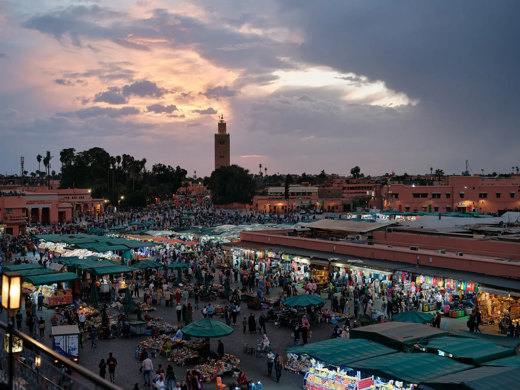 Markedsboder og folkemylder på Jemaa el-Fnaa-pladsen i skumringen med Koutoubia-minareten bagved