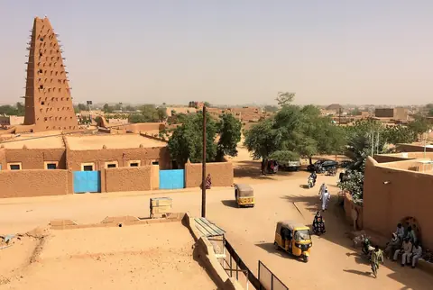 Den høje lerminaret ved den store moské i Agadez over lave lerhuse og sandede gader