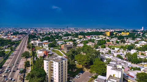 Brazzaville set fra oven med en bred boulevard, grønne kvarterer og højhuse under blå himmel