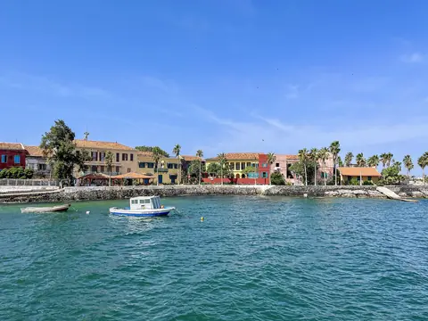 Farverige kolonihuse og palmer ved det turkise vand på øen Gorée ud for Dakar