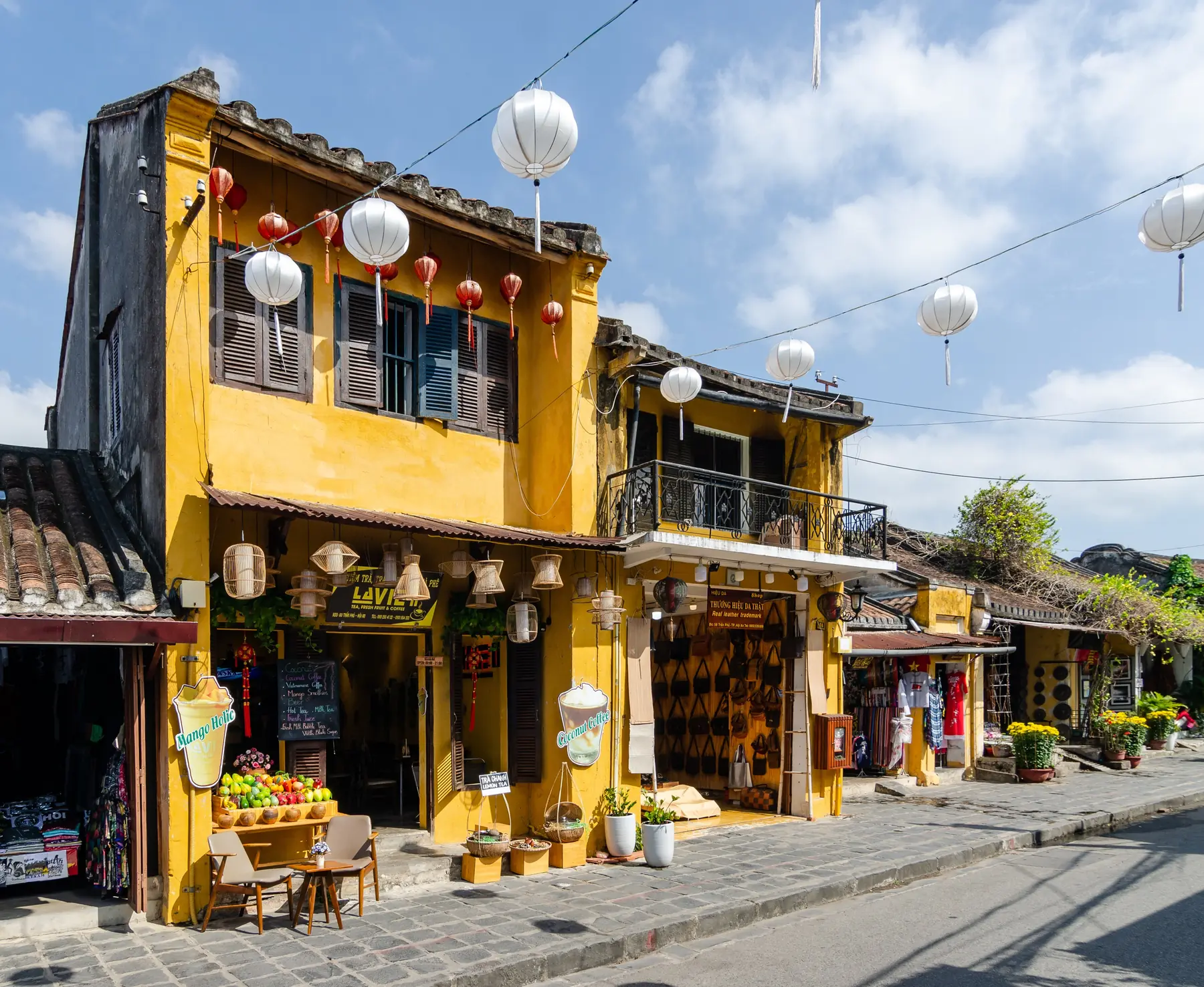 Gule huse med træbalkoner og hvide papirlanterner i en gade i den gamle by i Hoi An i Vietnam