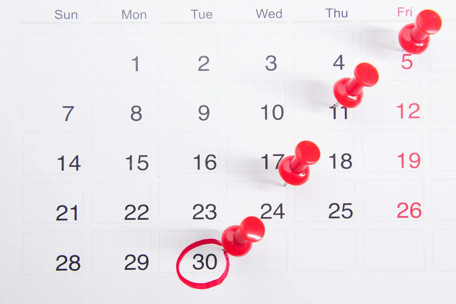 En månedskalender med røde knappenåle i flere datoer og en rød ring om den 30.