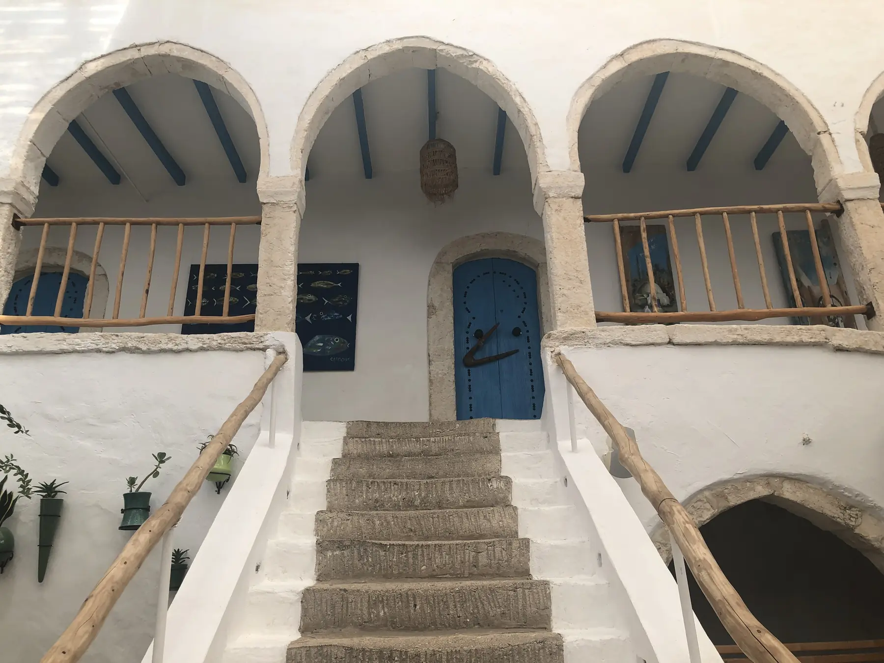 Hvidkalket hus med buegange, træbalustrader og en blå dør på øen Djerba i Tunesien