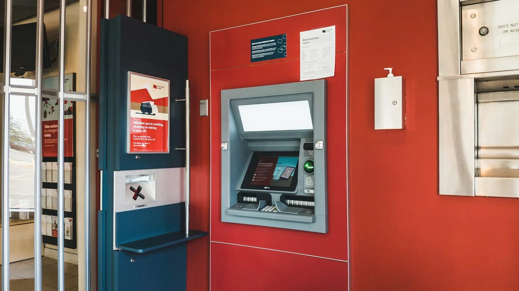 En pengeautomat indbygget i en rød væg i forhallen til en bank