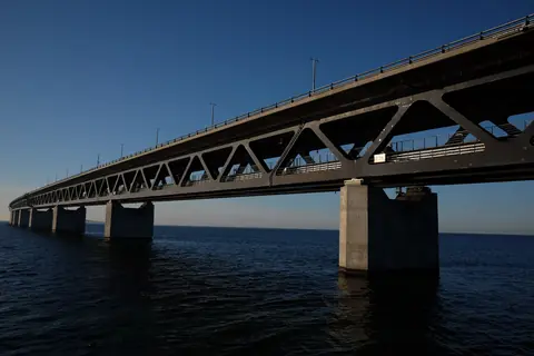 Øresundsbroens stålkonstruktion og betonpiller over mørkeblåt vand i klart aftenlys