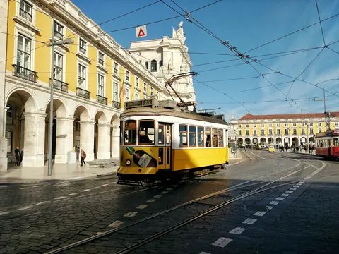 Gul sporvogn på linje 25 kører over brostenene ved Praça do Comércio i Lissabon