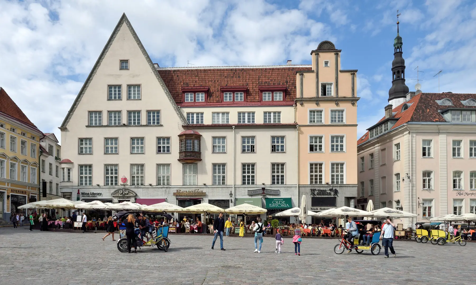 Gavlhuse og caféer med parasoller på Rådhuspladsen i Tallinns gamle by under blå himmel