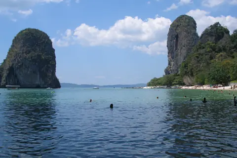 Høje kalkstensklipper og badende i det turkise vand ved stranden på Railay-halvøen i Krabi