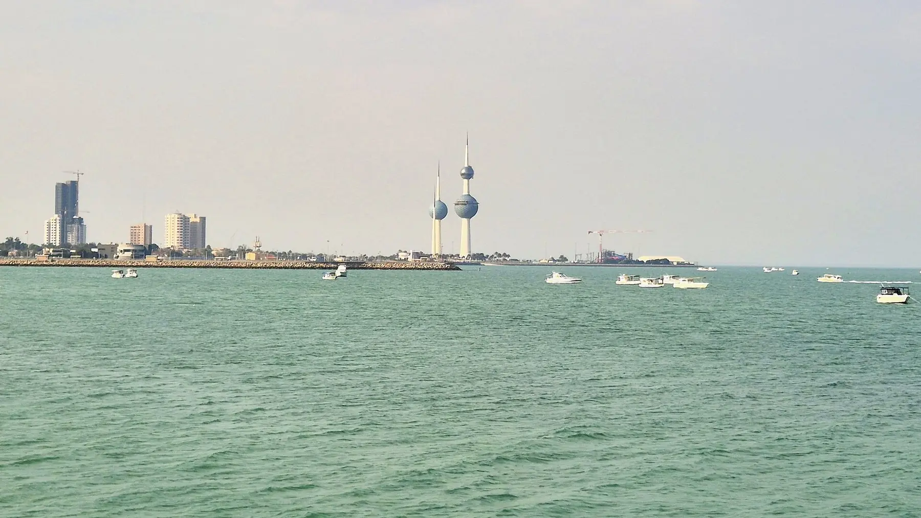 Kuwait Towers med de kugleformede tårne ved kysten, set fra det grønne hav med små både
