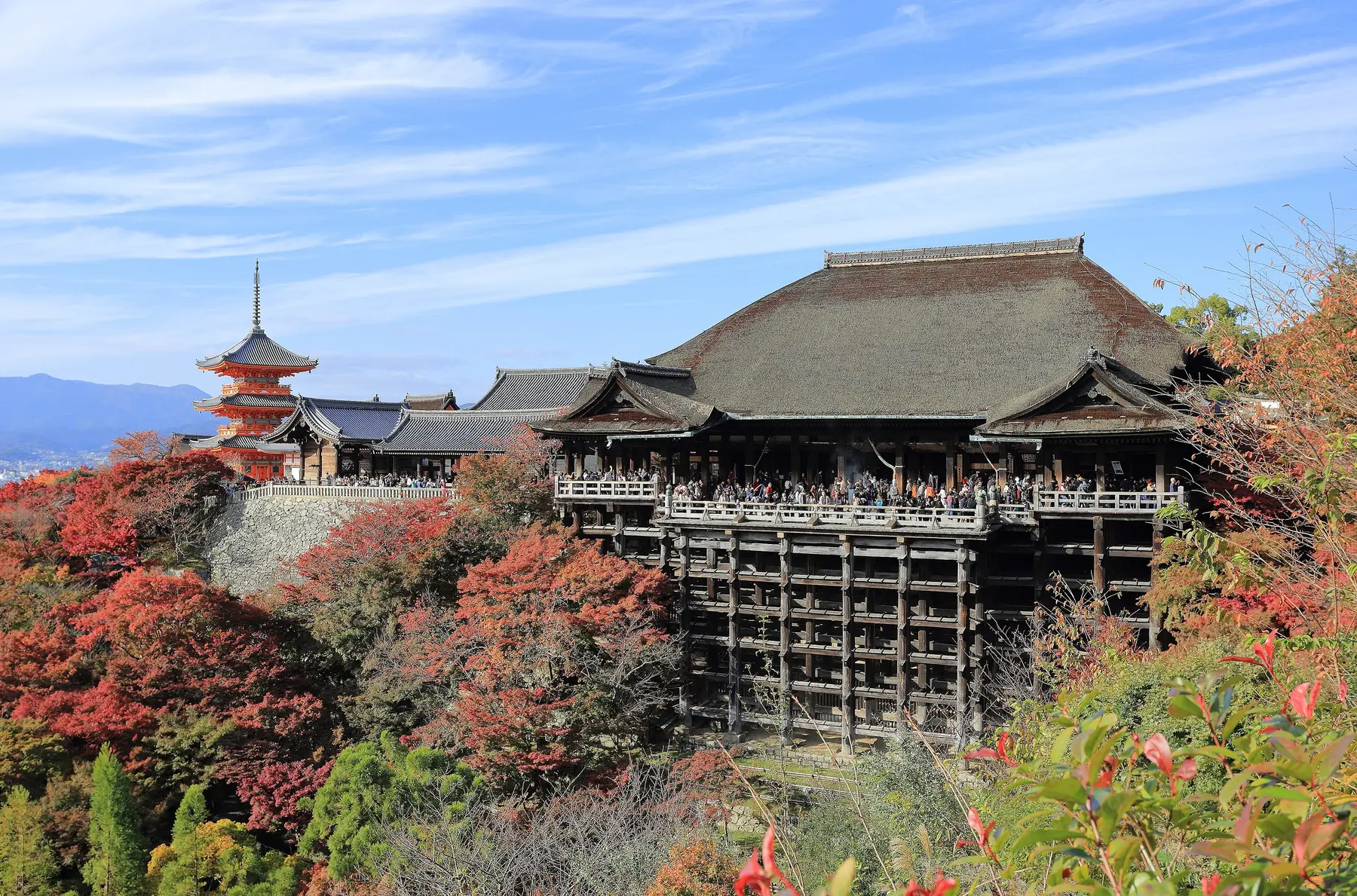 Templet Kiyomizu-dera med træterrassen og en rød pagode omgivet af efterårsfarvede ahorntræer i Kyoto