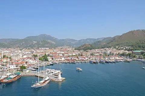 Marmaris' bugt med sejlbåde, et lille fyr og byens hvide huse foran grønne bjerge
