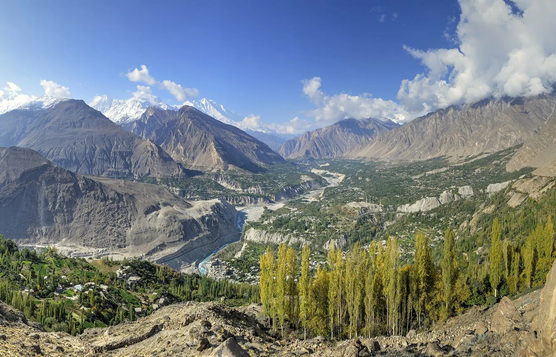 Hunza-dalen med efterårsgule popler, en snoet flod og høje bjergtoppe under blå himmel