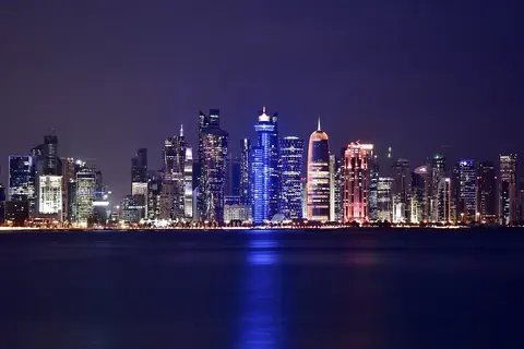 Dohas oplyste skyskrabere i West Bay spejler sig i vandet en aften, set fra Corniche