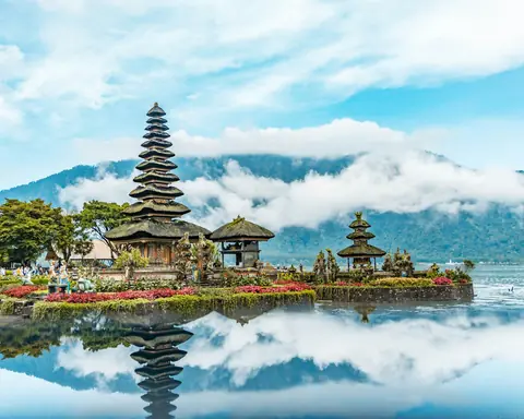 Vandtemplet Pura Ulun Danu Beratan med det høje pagodetag spejler sig i søen foran skyomkransede bjerge på Bali