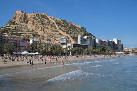 Postiguet-stranden i Alicante med borgbjerget og Santa Bárbara-borgen bag byens huse