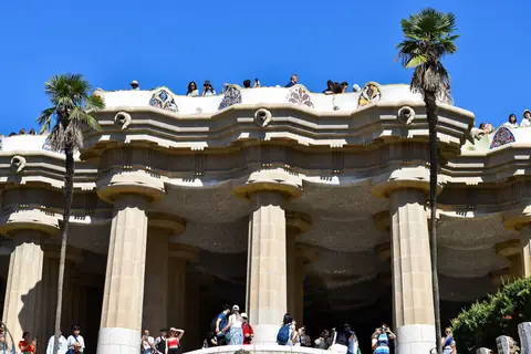 Søjlegangen under terrassen i Gaudís Park Güell i Barcelona med palmer og besøgende