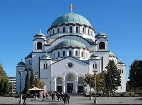 Sankt Sava-kirken i Beograd med hvid facade og grønne kobberkupler under klar blå himmel