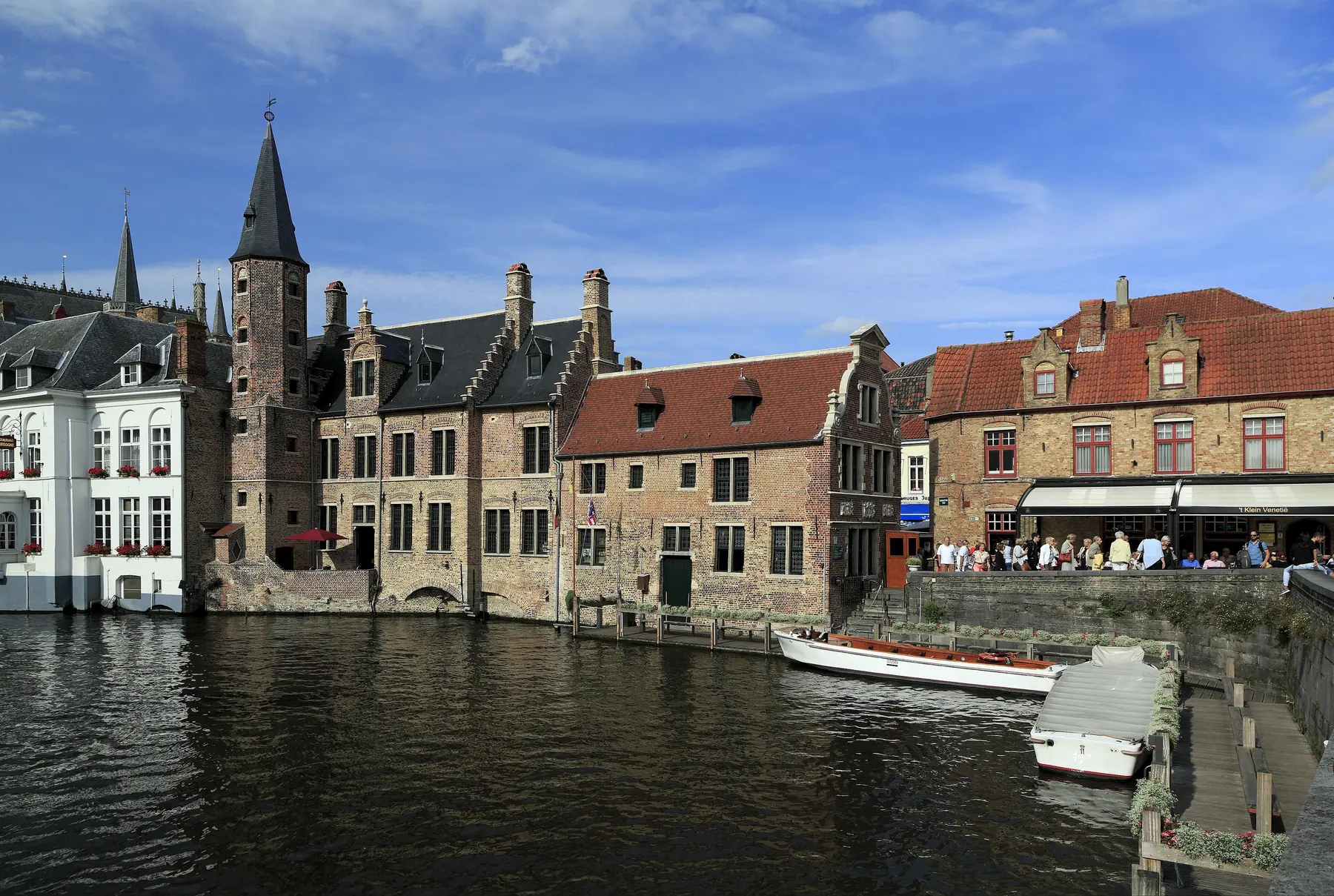 Middelalderlige murstenshuse og et tårn ved kanalen Rozenhoedkaai i Brugge med en turistbåd