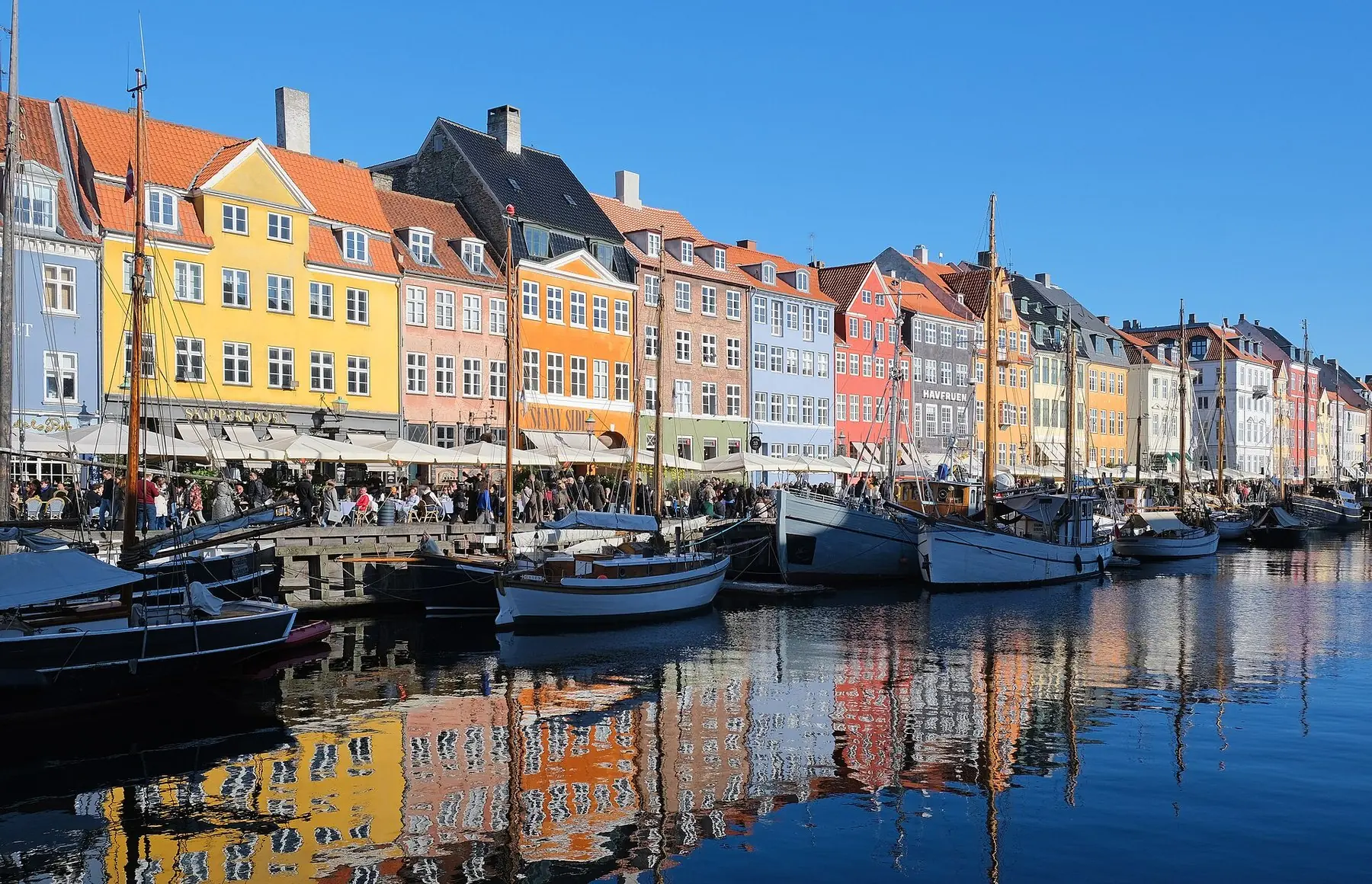 Farverige gavlhuse og gamle sejlskibe langs kanalen i Nyhavn i København