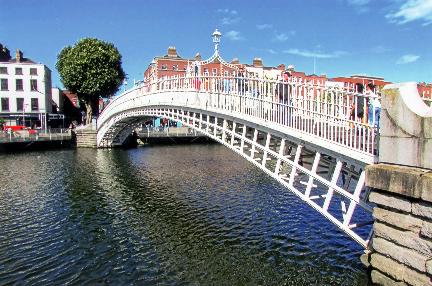 Den hvide støbejernsbro Ha'penny Bridge over floden Liffey i Dublin en solskinsdag