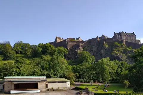 Edinburgh Castle på klippen over de grønne Princes Street Gardens en solskinsdag