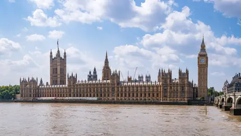 Parlamentsbygningen Palace of Westminster og Big Ben ved Themsen i London under hvide skyer