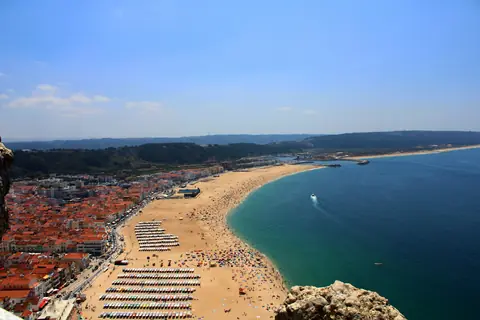 Den lange sandstrand i Nazaré med strandtelte, røde tage og Atlanterhavet set fra klippen Sítio