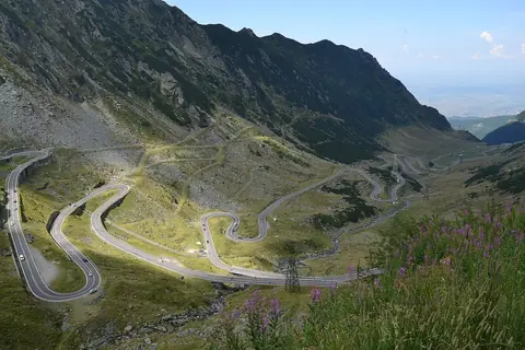Vejen Transfăgărășan snor sig i serpentiner op ad en grøn bjergdal i Făgăraș-bjergene