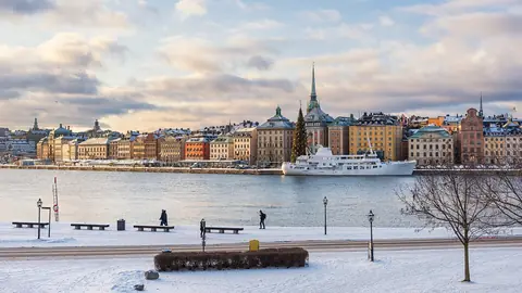 Gamla stans farverige huse og kirketårne ved vandet set over en snedækket kaj i Stockholm