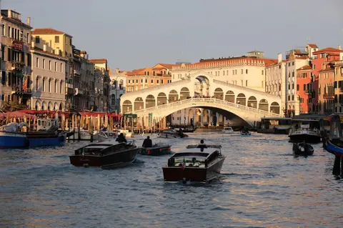 Motorbåde på Canal Grande foran Rialtobroen i Venedig i aftenlys
