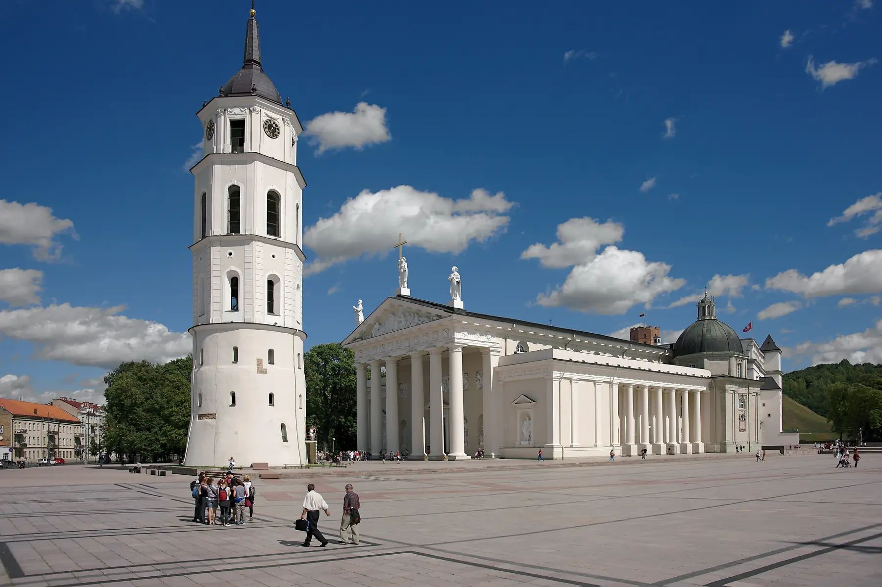 Det hvide klokketårn og Vilnius-katedralens søjlefacade på Katedralpladsen under blå himmel med hvide skyer