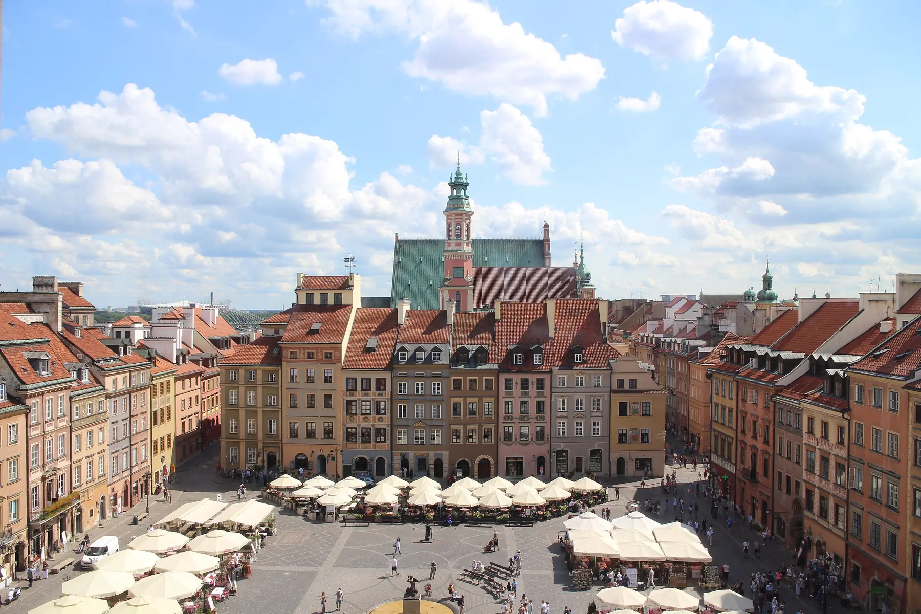 Det gamle torv i Warszawa med farverige borgerhuse og caféparasoller set fra oven