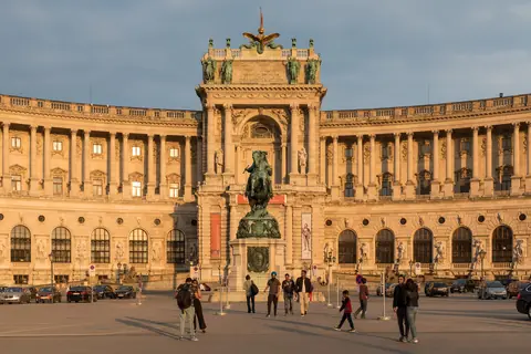 Den buede facade på Neue Burg ved Heldenplatz i Wien i gyldent aftenlys med rytterstatue