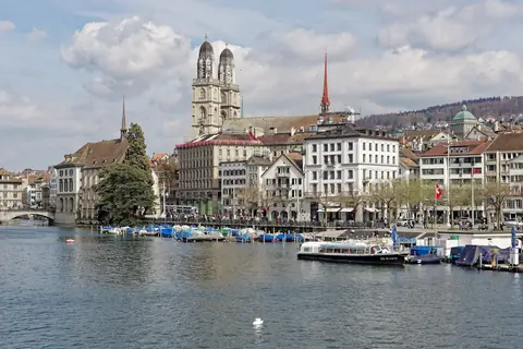 Floden Limmat i Zürich med Grossmünsters tvillingetårne, gamle huse og en udflugtsbåd