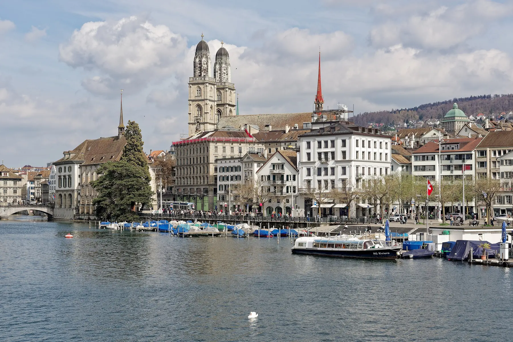Floden Limmat i Zürich med Grossmünsters tvillingetårne, gamle huse og en udflugtsbåd