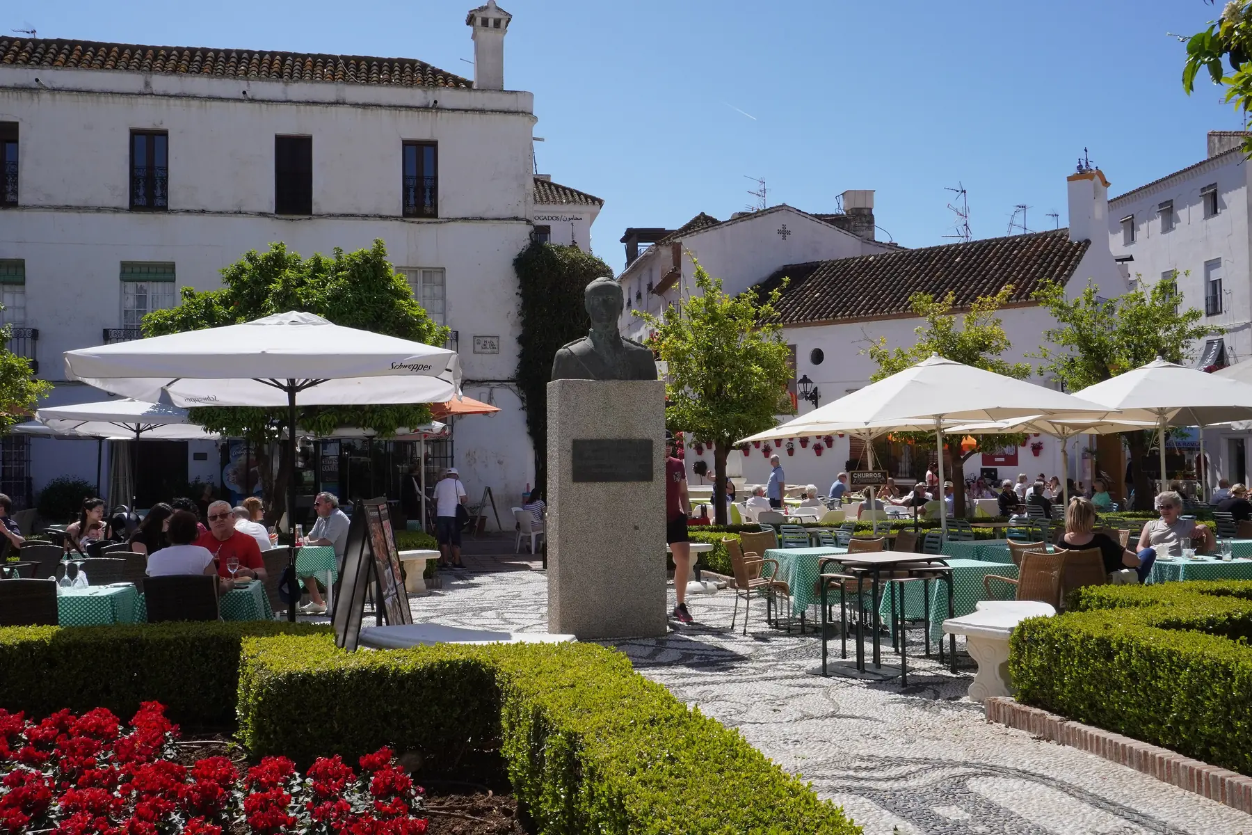 Udendørsserveringer under parasoller og hvide huse på Plaza de los Naranjos i Marbella