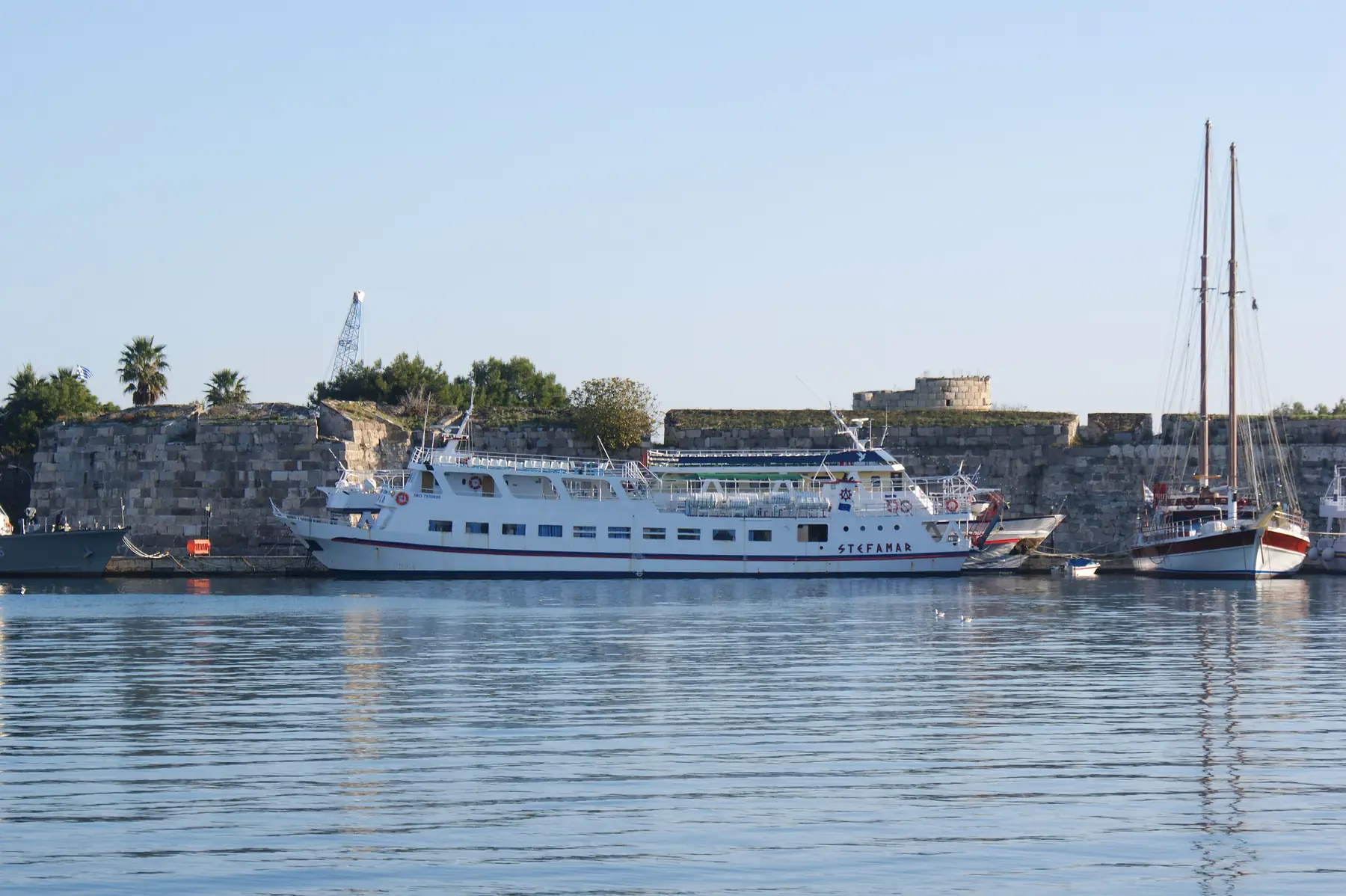 Udflugtsbåd og sejlskib i havnen i Kos by foran ridderborgens mure