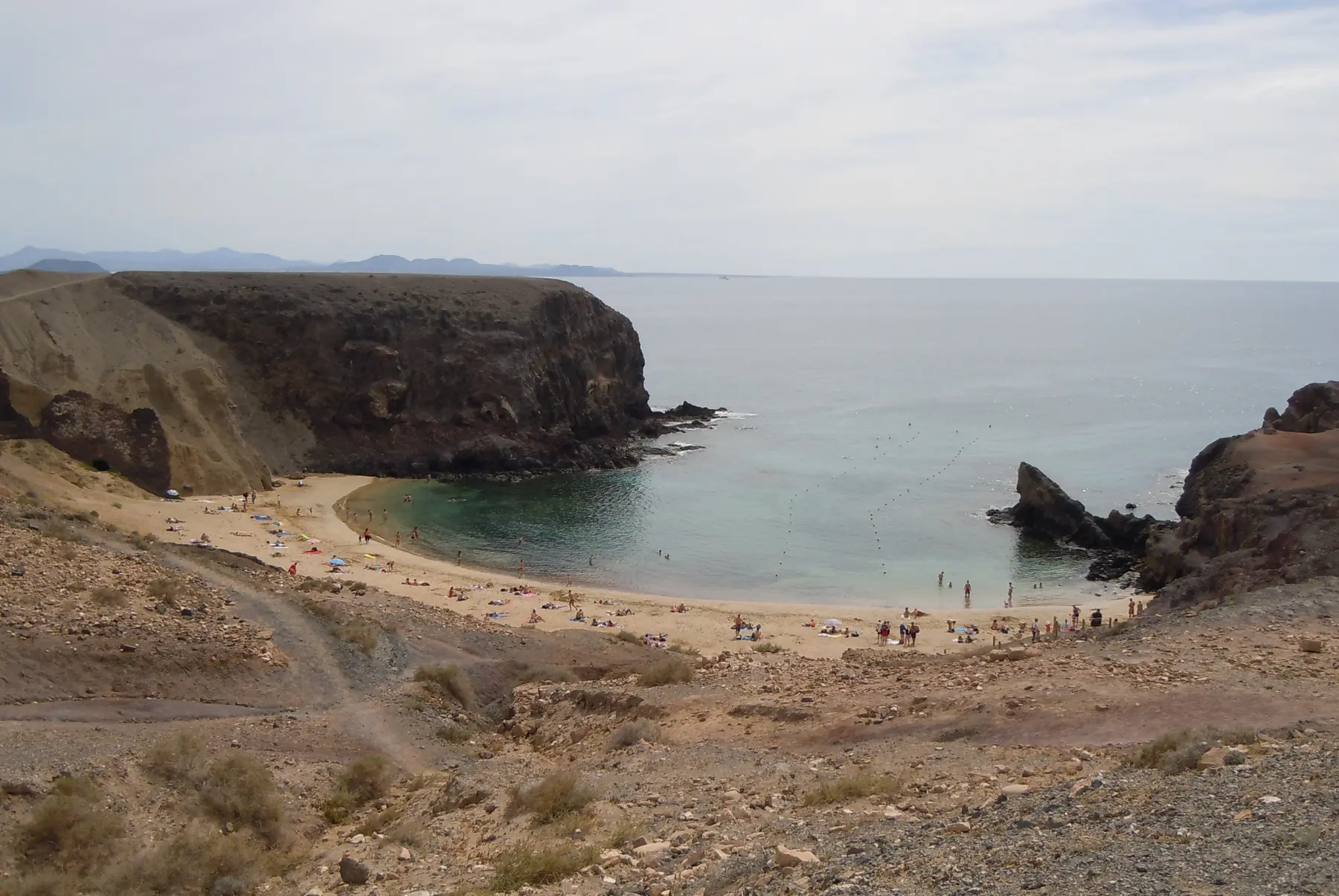 Badegæster på den lille bugt Playa Papagayo mellem mørke klipper på Lanzarote
