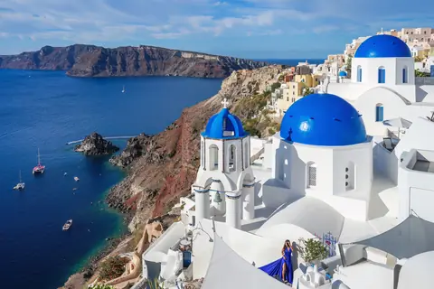 Hvide kirker med blå kupler over kalderaen og havet i Oia på Santorini