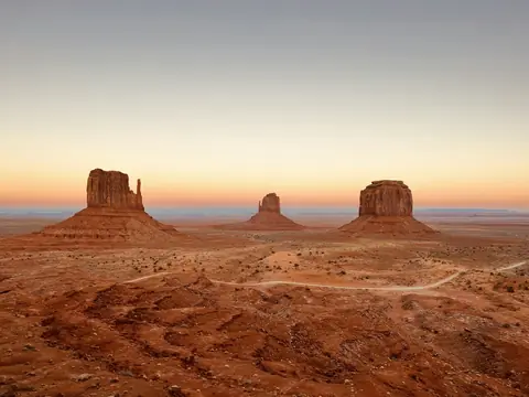 Klippeformationerne i Monument Valley i rødt ørkenlandskab under en lys skumringshimmel