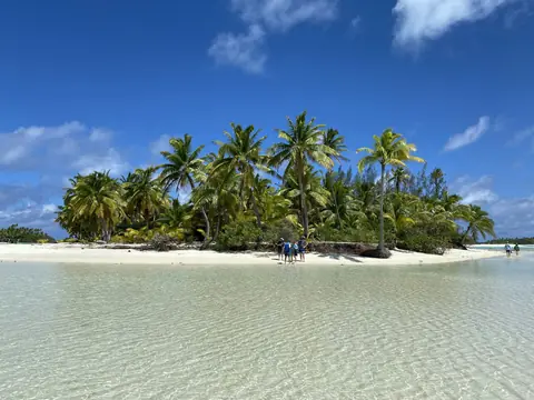 Palmeklædt ø med hvid sandstrand og krystalklart lavt vand i lagunen ved Aitutaki på Cookøerne