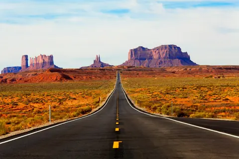 Lige landevej gennem rød ørken mod klippeformationerne ved Monument Valley i USA