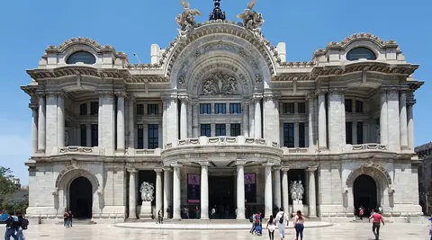 Den hvide marmorfacade på Palacio de Bellas Artes i Mexico City med statuer og besøgende på pladsen