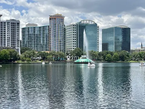Springvandet i Lake Eola i Orlando med svanebåde og højhuse i downtown bag søen