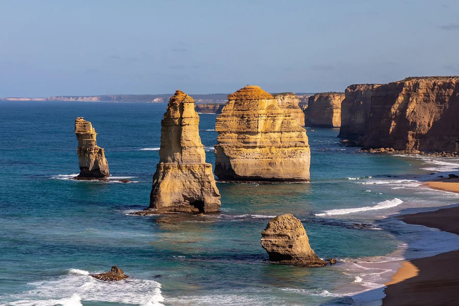Kalkstensstakkene Twelve Apostles i det blå hav foran gyldne klipper ved Great Ocean Road
