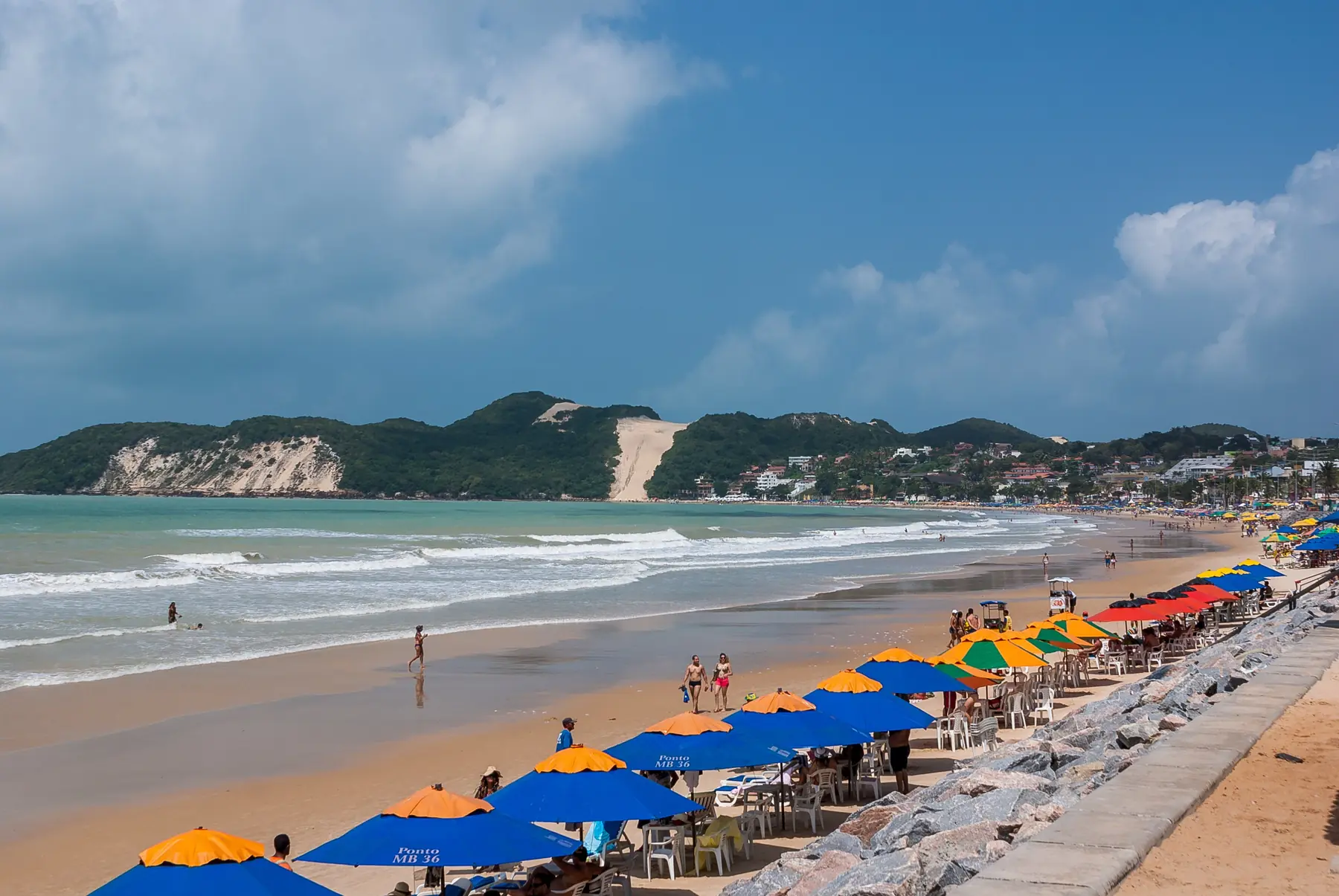 Farverige parasoller på stranden Ponta Negra i Natal med klitten Morro do Careca i baggrunden